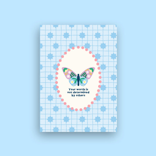 A square art print or card featuring a pastel butterfly illustration inside a pink dotted oval, with the text 'Your worth is not determined by others' on a light blue grid background with blue star motifs. The print is centered on a solid light blue background.